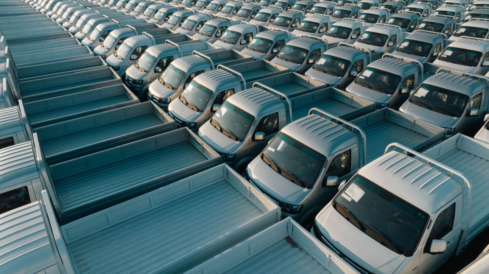 Aerial stock photo of rows of parked pickup trucks, standing in for idle farm machinery